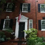 Red brick townhouse with black shutters, white doorway, and an American flag above the front steps