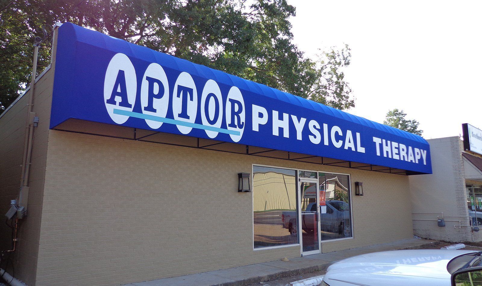 A building with a blue awning that says aptor physical therapy
