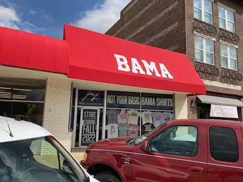 A red truck is parked in front of a bama store.