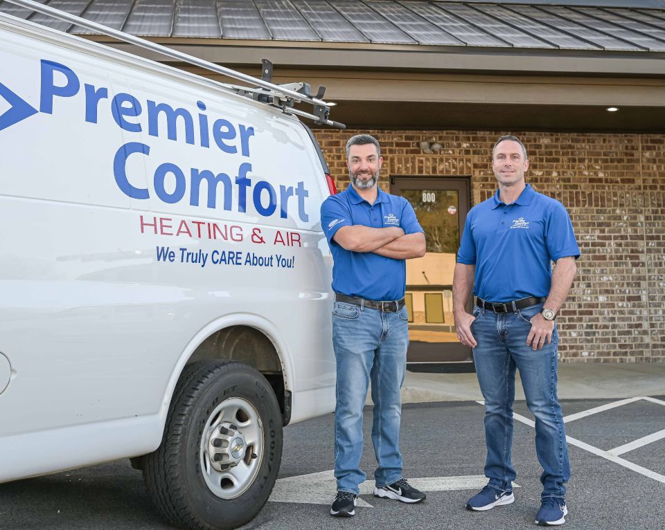 Two men in blue shirts pose by a white van with 