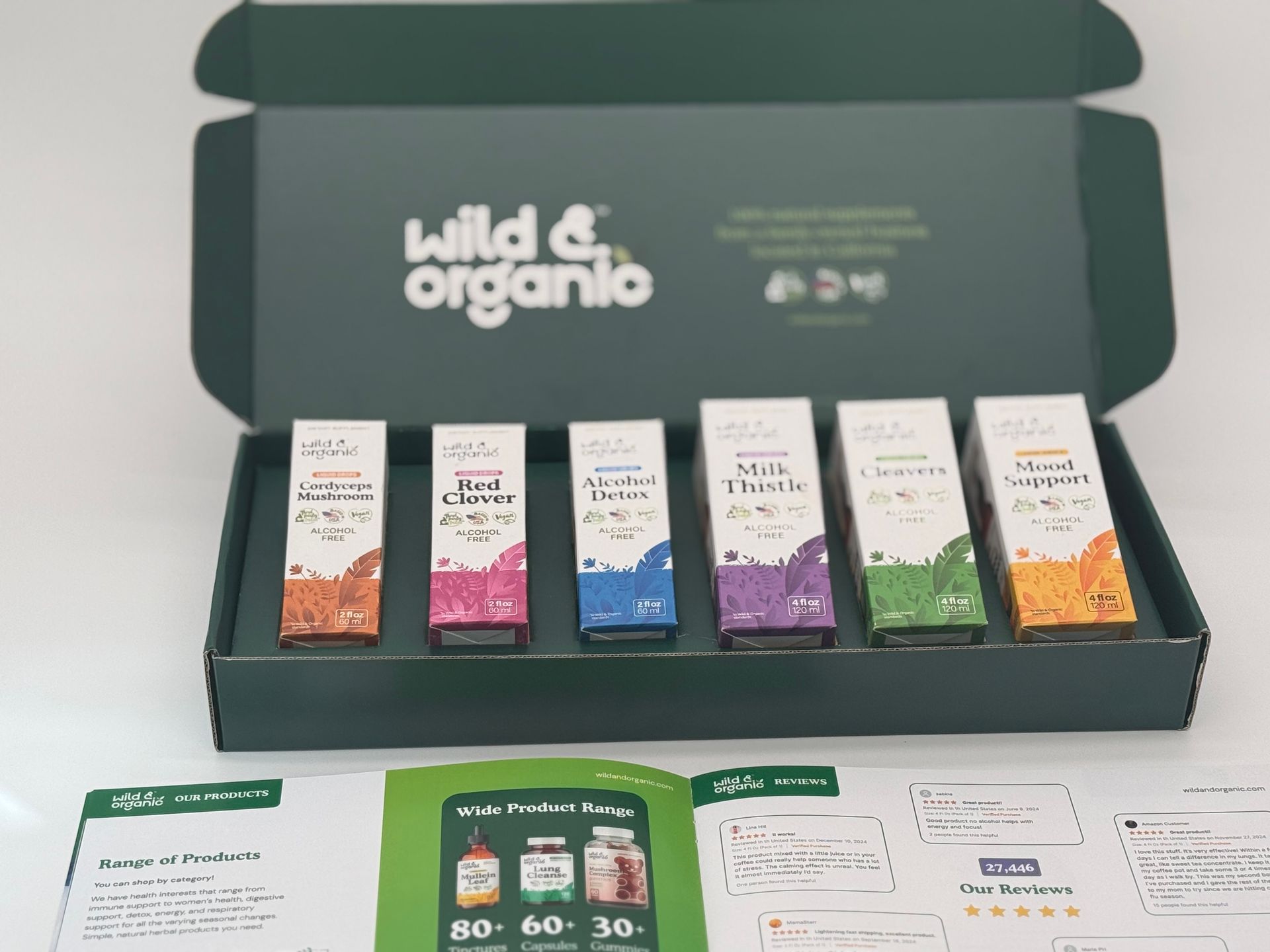 Open box of Wild & Organic supplements with six bottles in colorful boxes, papers below.