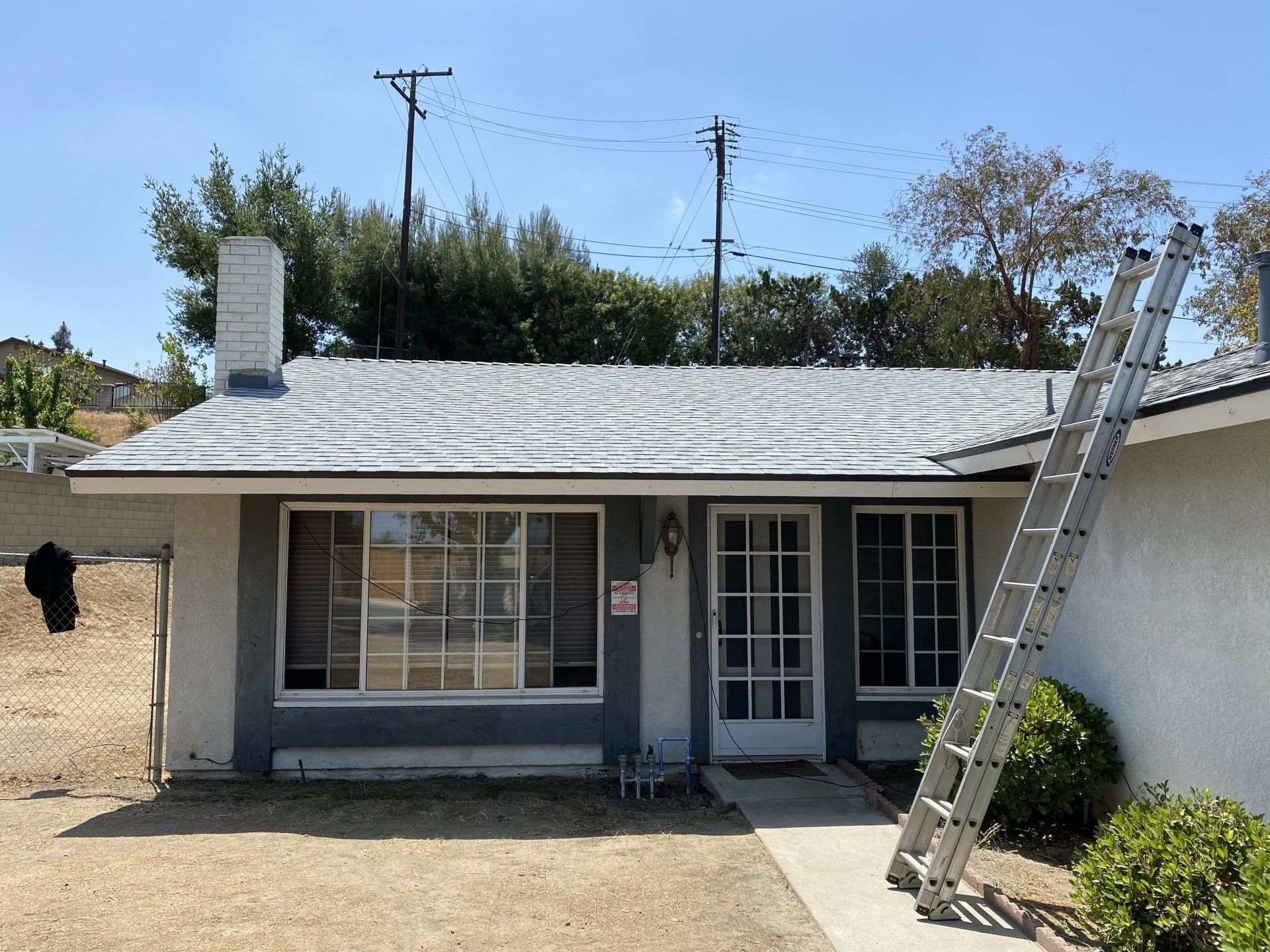 Small, gray house with a ladder leaning against it