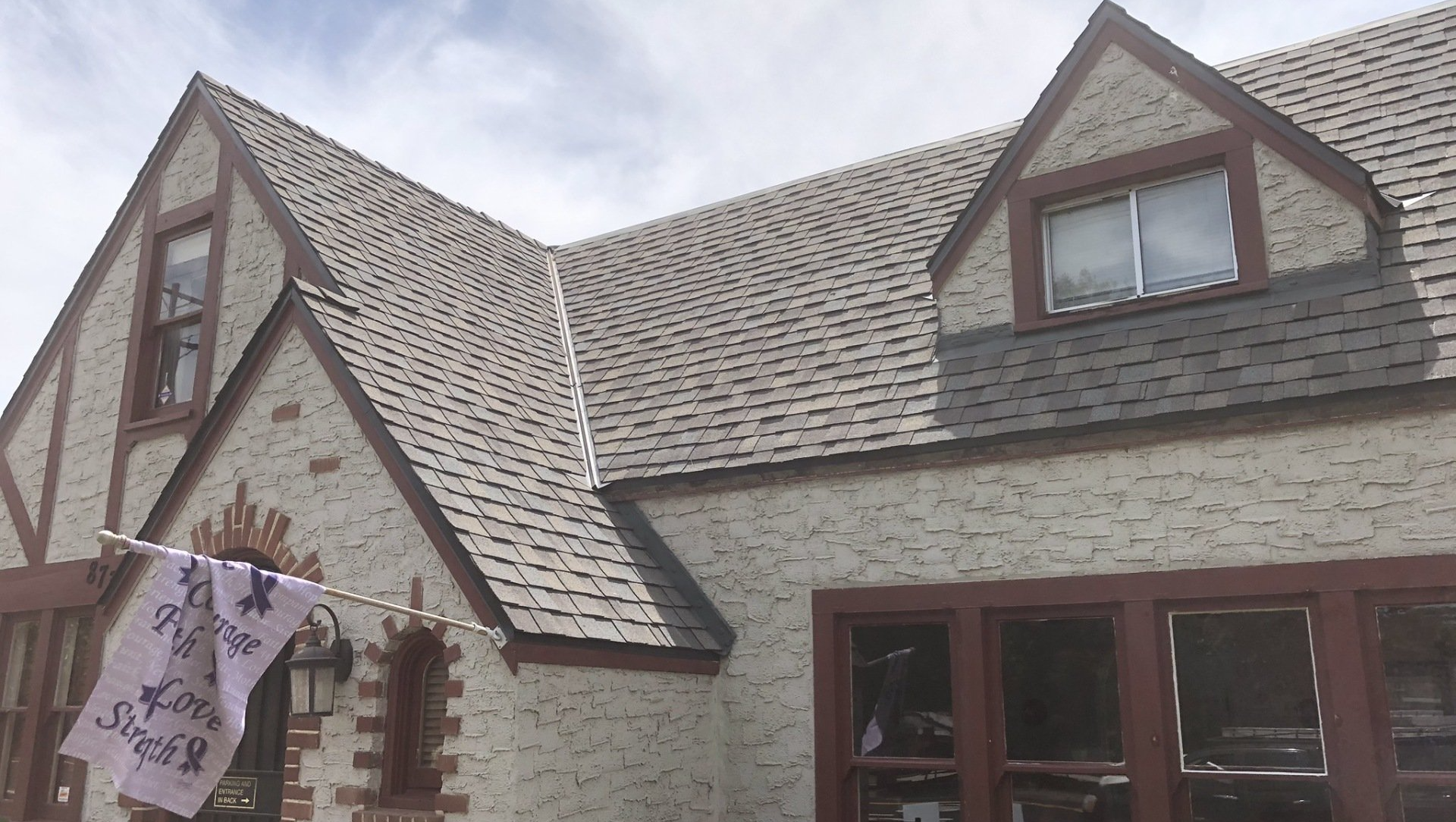 Gloved hand placing shingle on asphalt roof