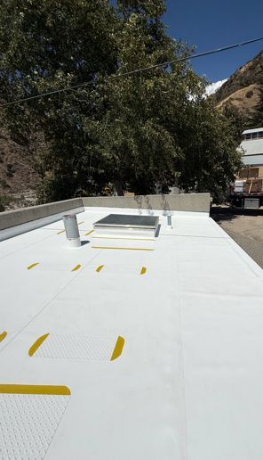 Roofer on flat roof installing material, with landscape area and mountains in background