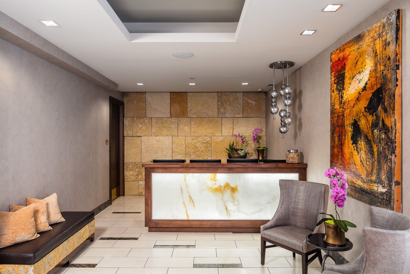Interior lobby with a reception desk, seating area, stone wall, and wall art.