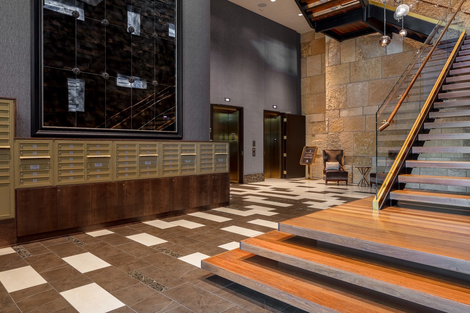 Interior lobby with mailboxes, elevators, and a staircase in a modern apartment building.