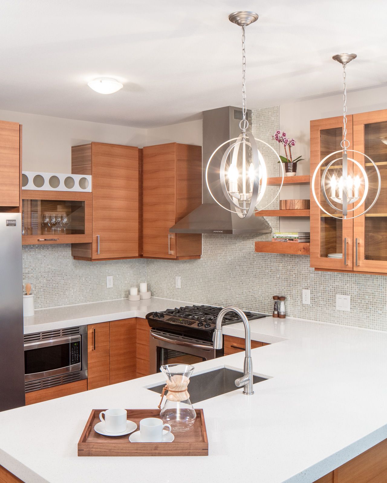 A modern kitchen with warm wood cabinets, white quartz countertops, a central island, and pendant lights.