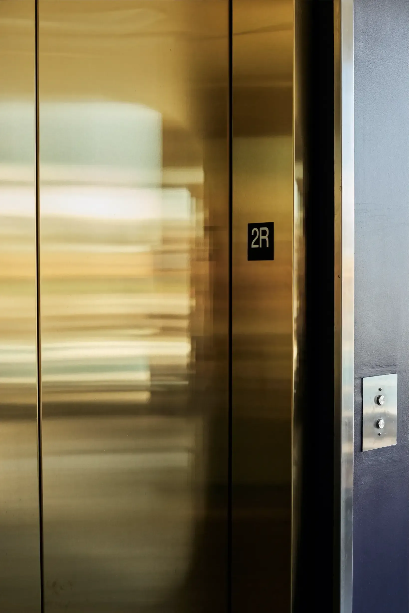 Elevator doors with a 2R floor marker in a building hallway.