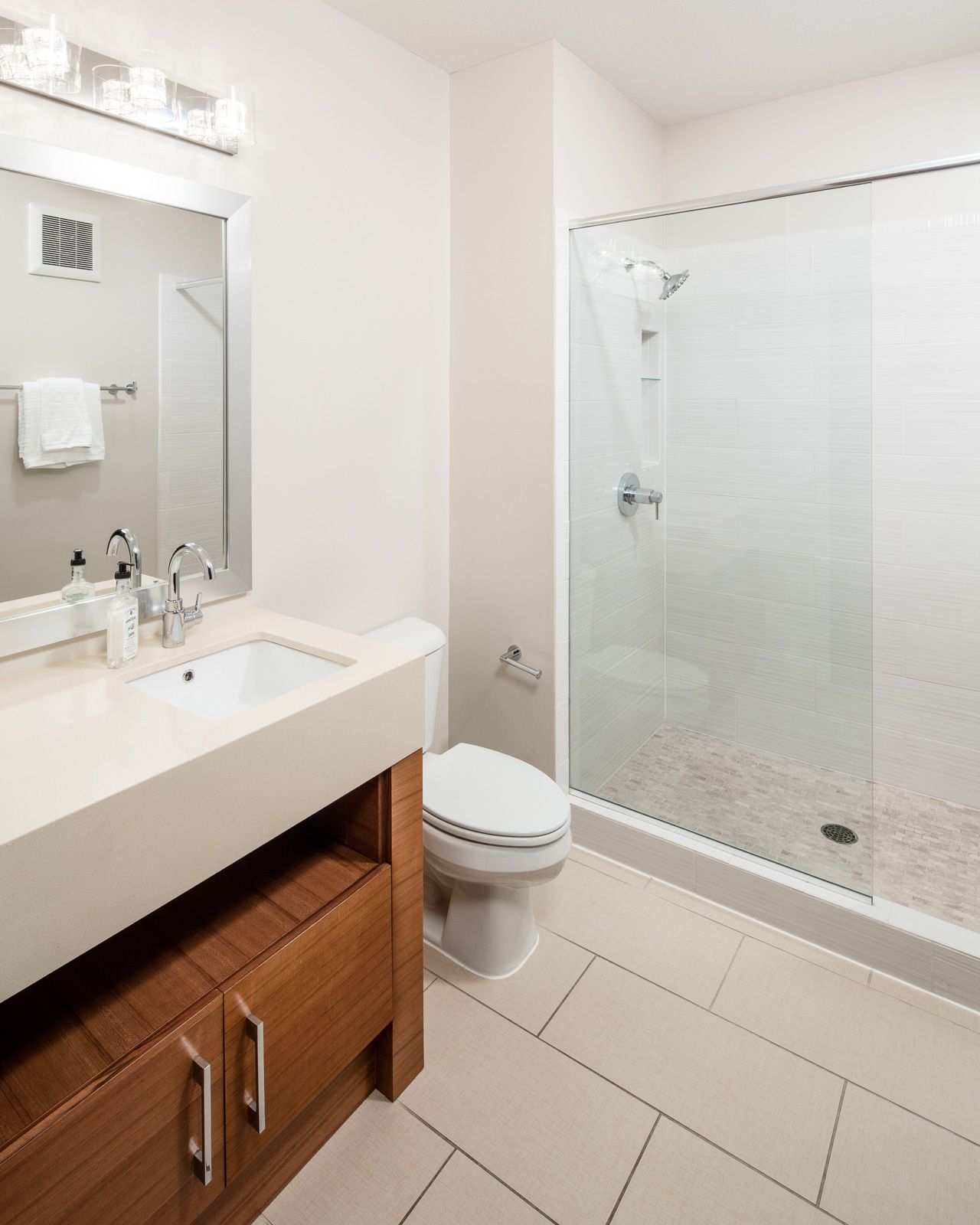 Bathroom with a vanity, sink, toilet, and glass-enclosed shower.