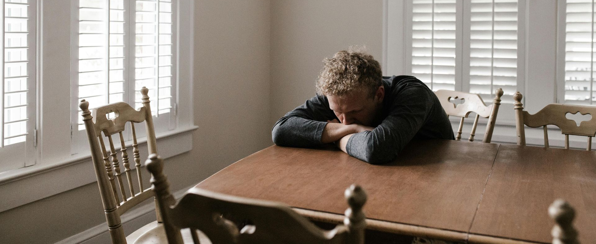 man with depression at kitchen table