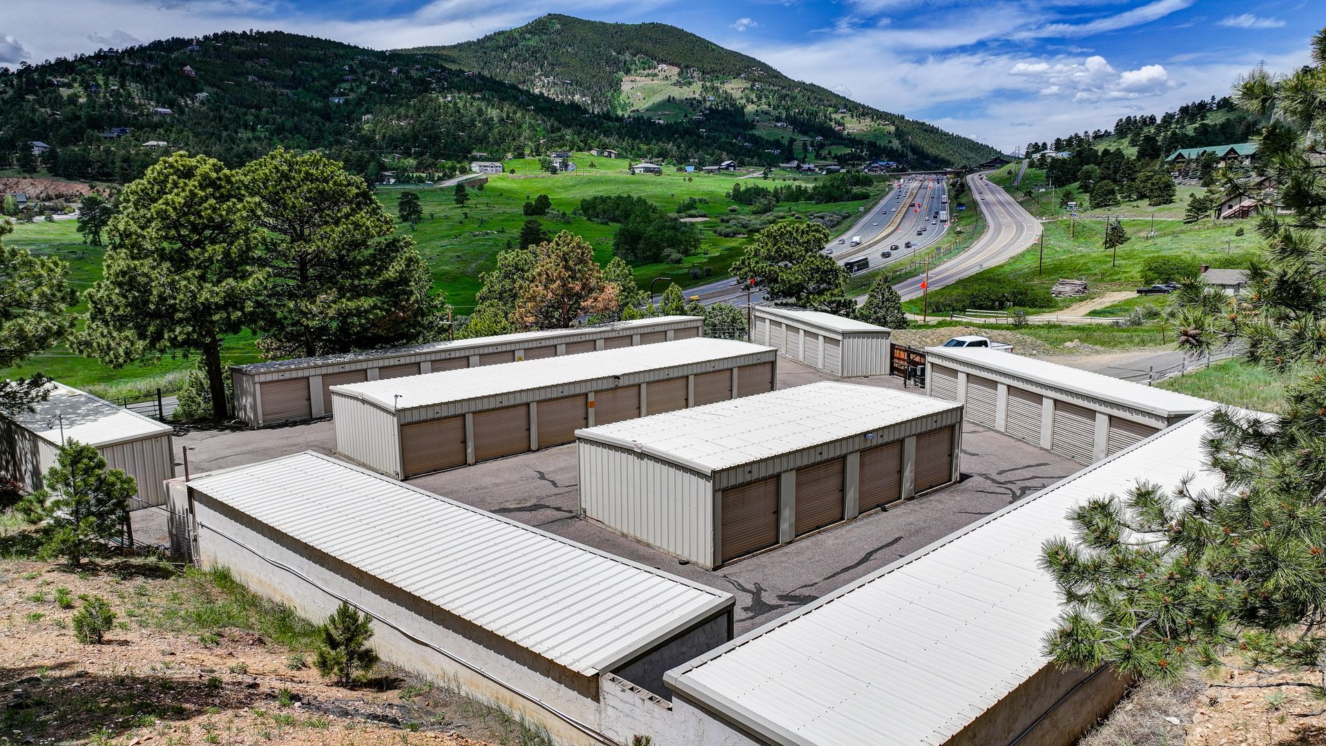 Storage units nestled among trees in a green, mountainous setting.