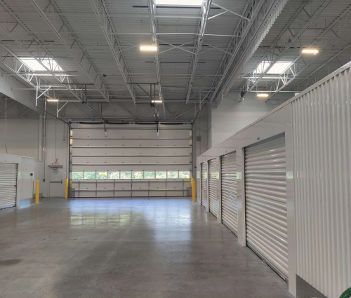 Interior of a storage facility with roll-up doors, concrete floor, and skylights.