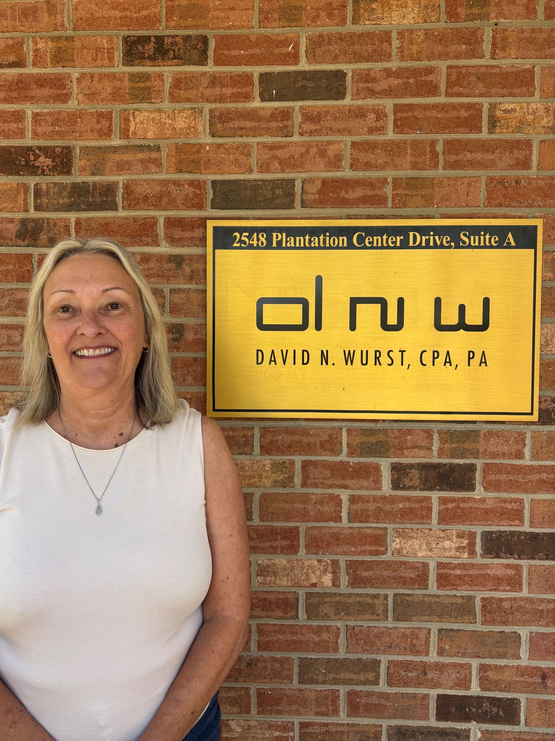 Smiling woman in a gray dress standing in a softly lit office.