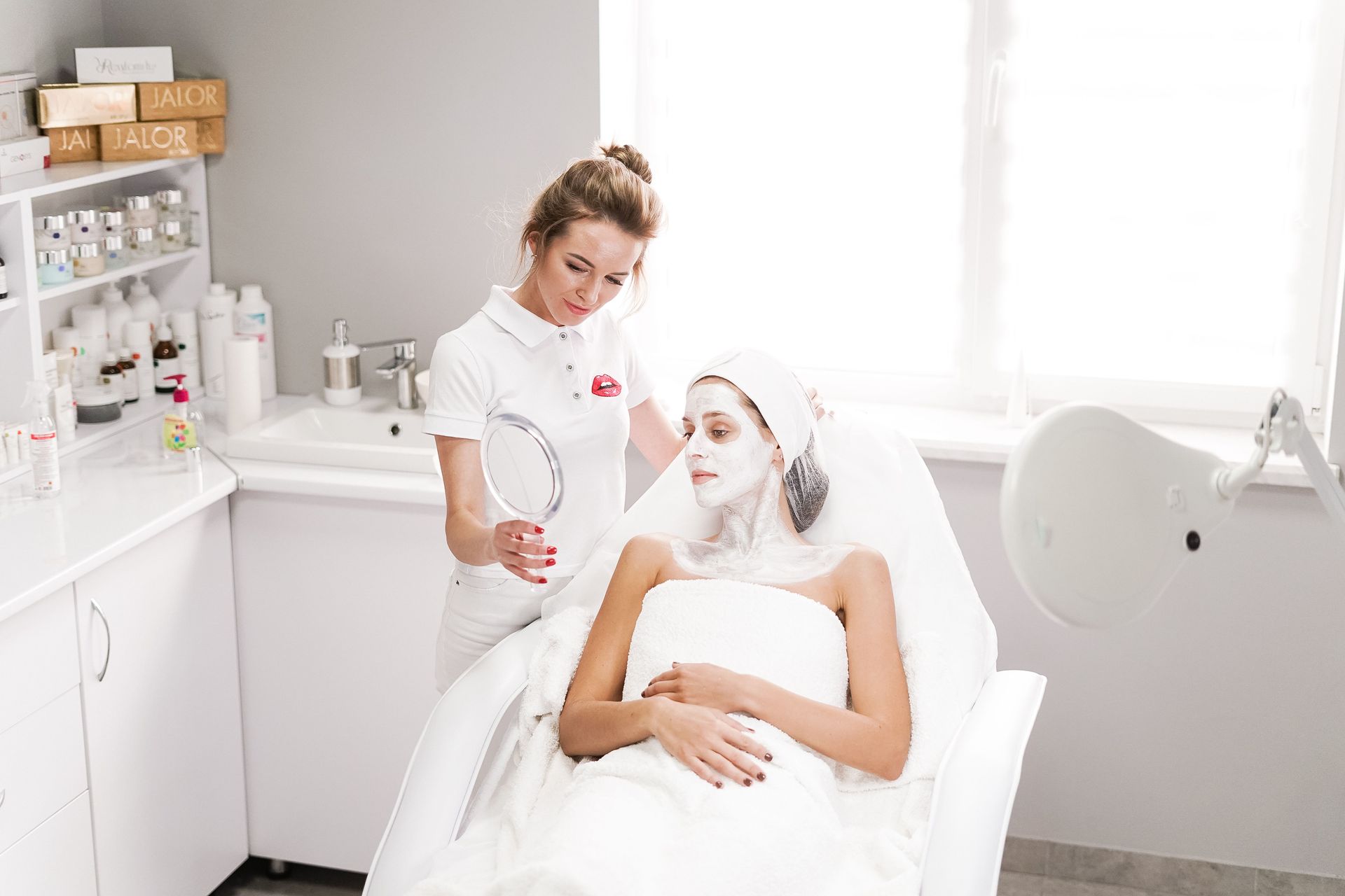 Therapist preparing a client for a facial in a bright clinic room