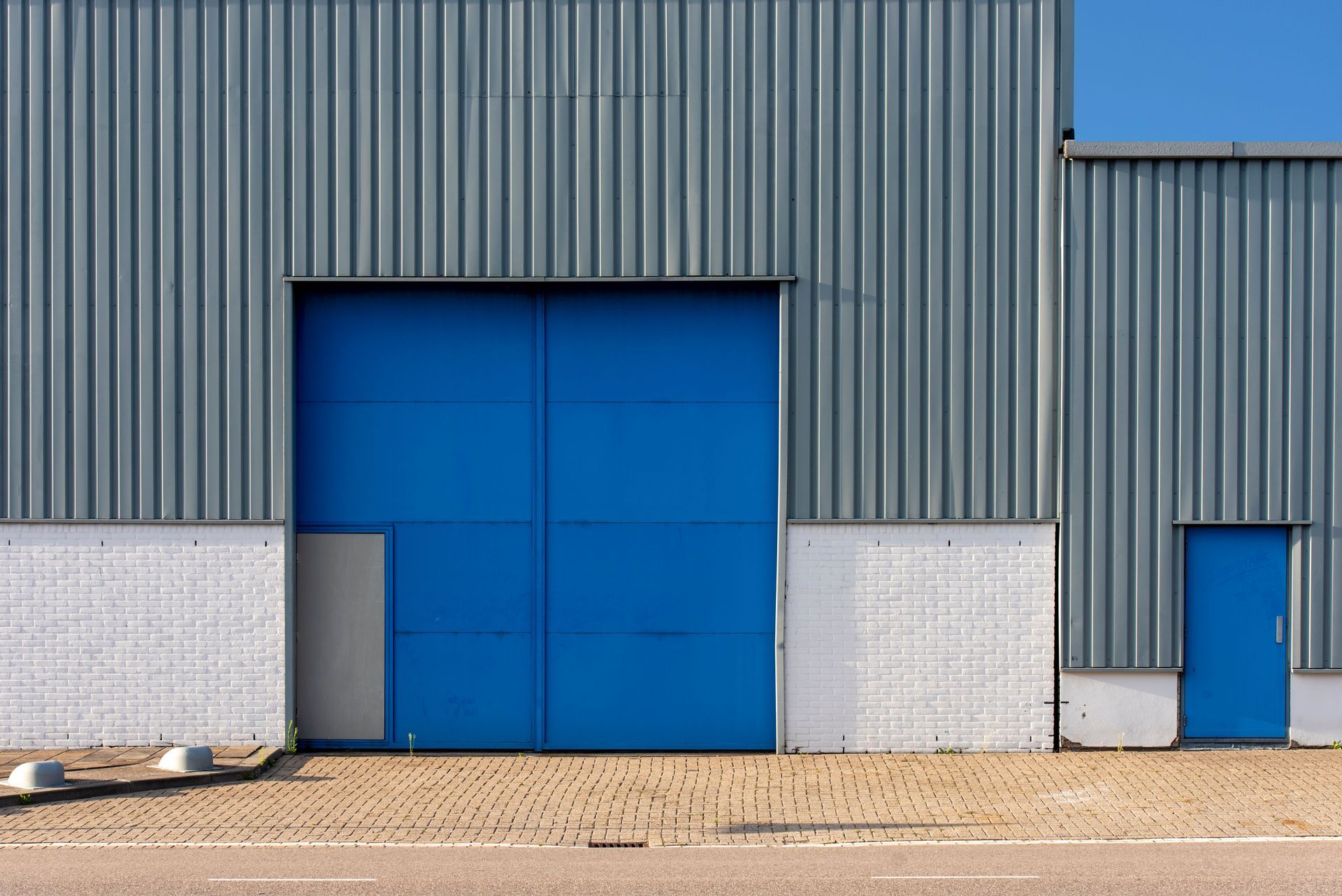 Warehouse with grey metal cladding and blue loading doors