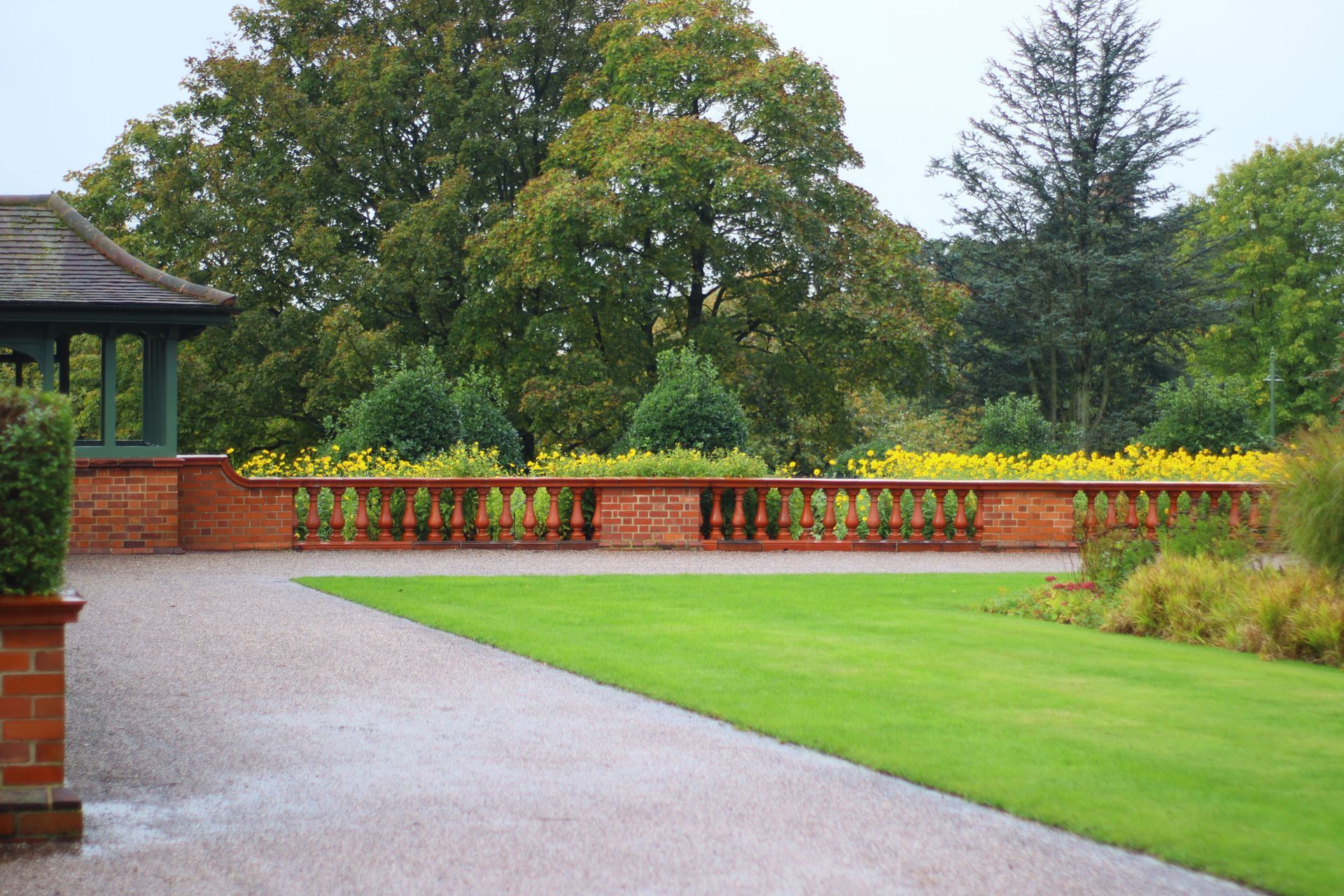 Landscaped garden with a lawn, low brick wall and paved path
