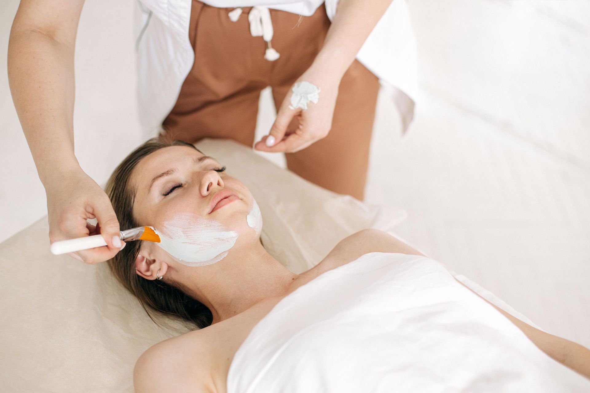 Therapist brushing a treatment mask onto a client's face