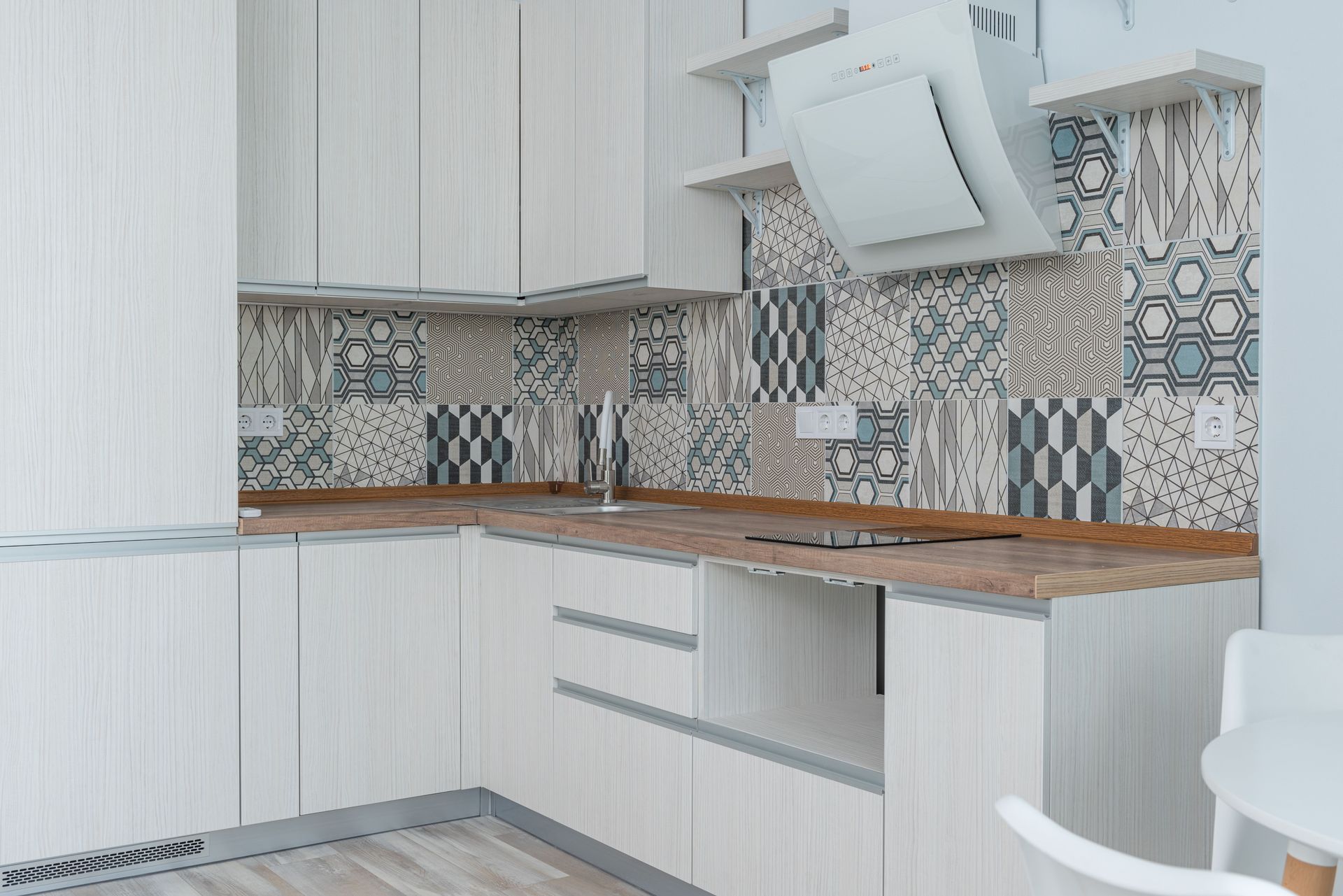 Kitchen with a patterned tile splashback above a timber worktop