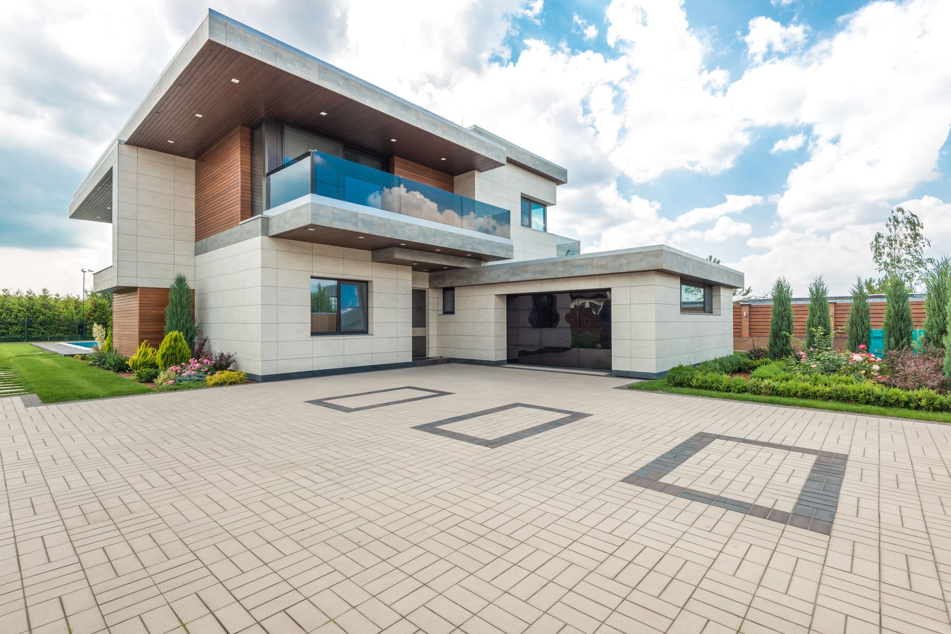 Modern house with a large grey paved driveway and planted borders