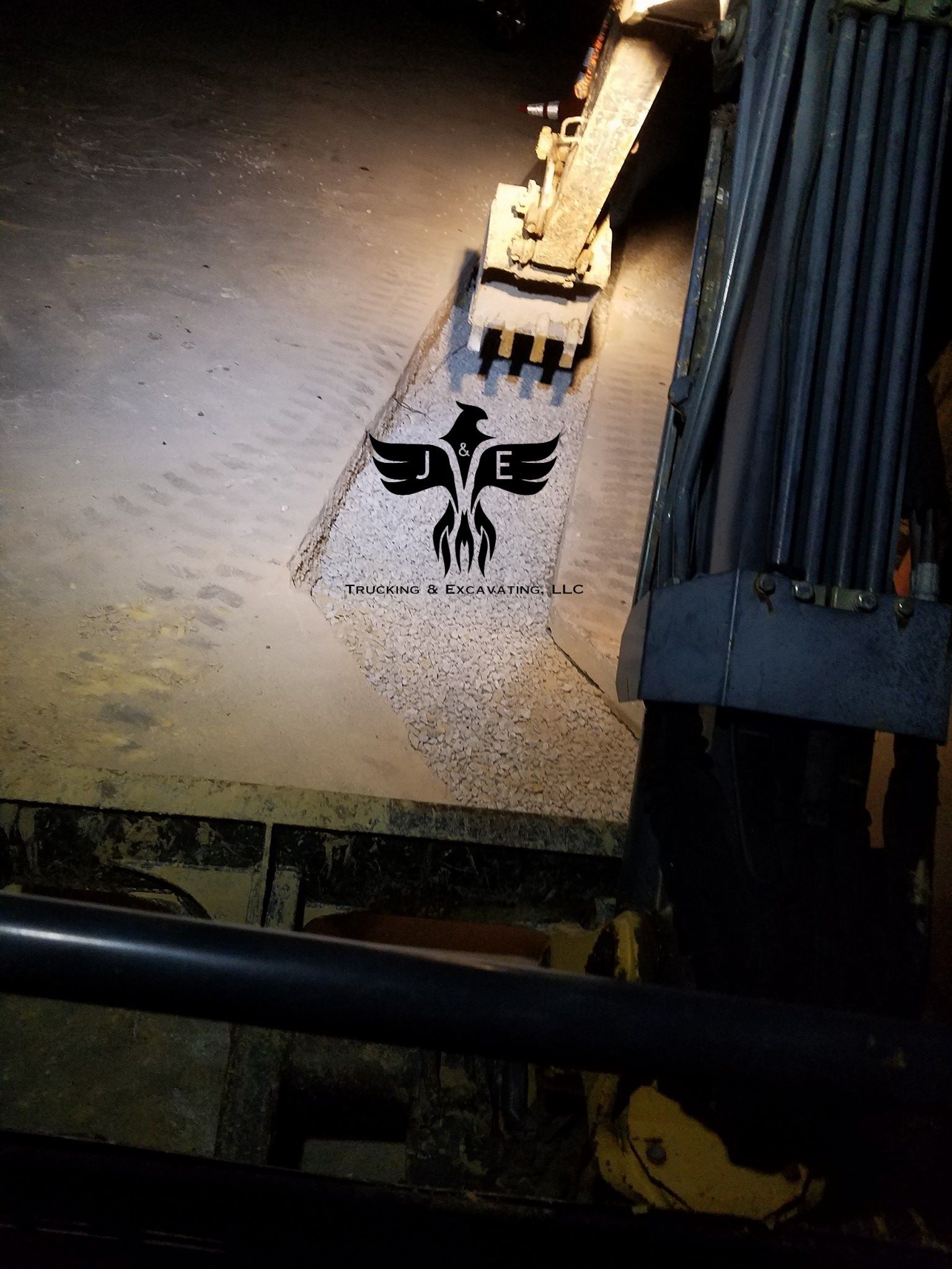 Aerial view of a beige surface with a black eagle-like emblem beside a building wall and machinery.