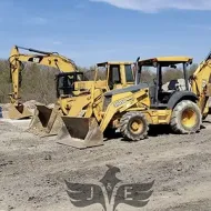 Yellow construction excavators and loaders parked on a gravel lot under a clear blue sky
