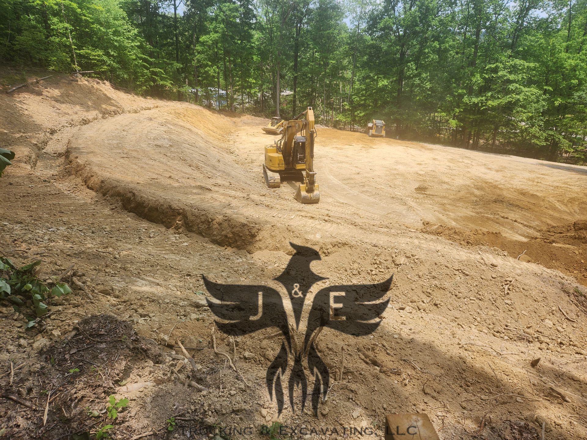 Bulldozer on a dirt slope with a large black eagle emblem in the foreground