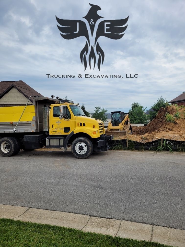 Yellow dump truck and excavator at a roadside construction site with a trucking and excavating logo above.