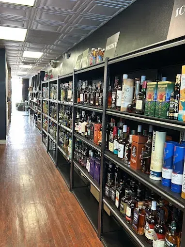 A narrow liquor store aisle with shelves of assorted bottles lining both sides and a wood floor.