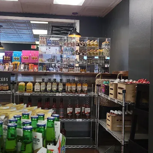 Liquor store aisle with beer and wine bottles, boxed goods, and shelves of snacks and collectibles