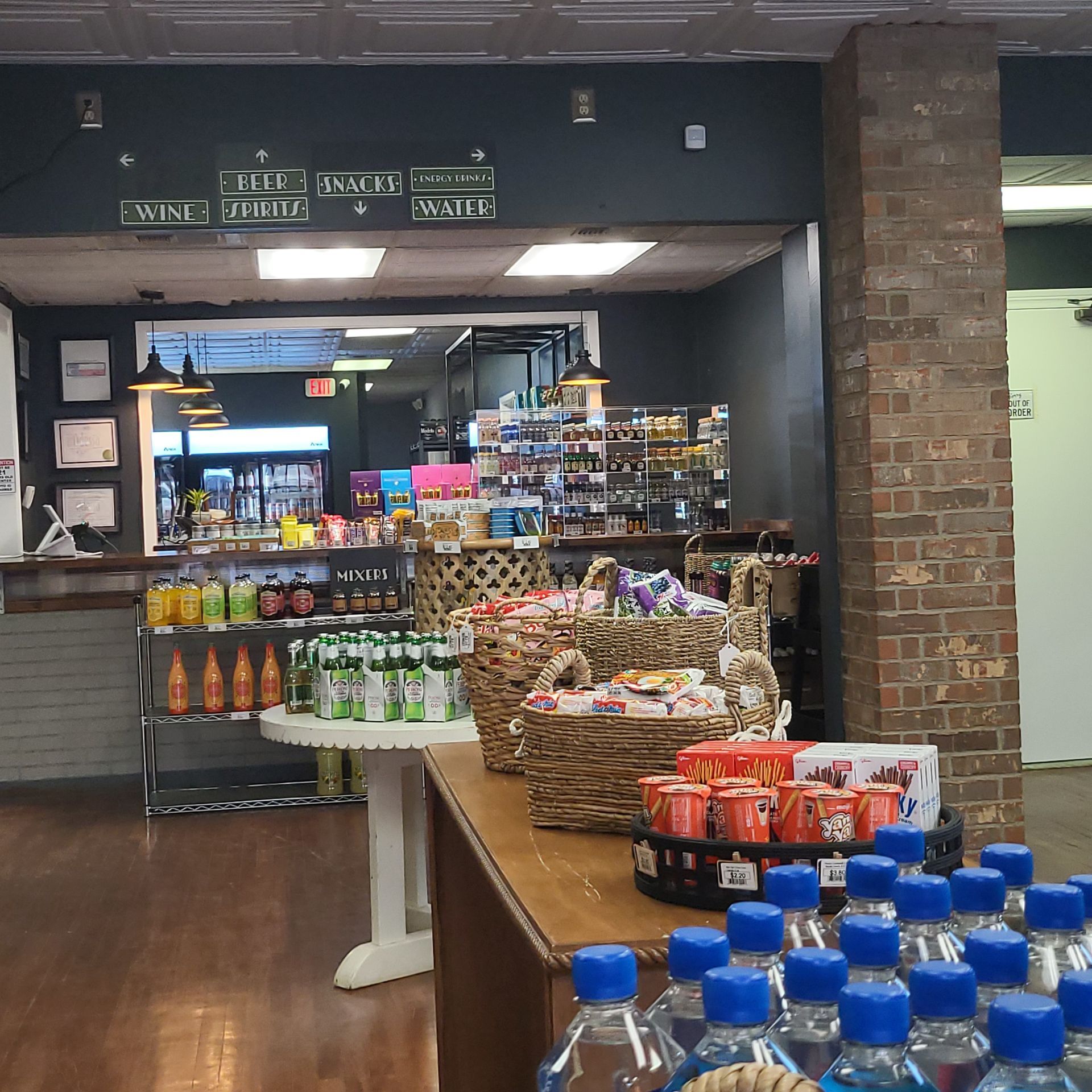 Grocery store aisle with bottled drinks and snacks on display near a deli counter