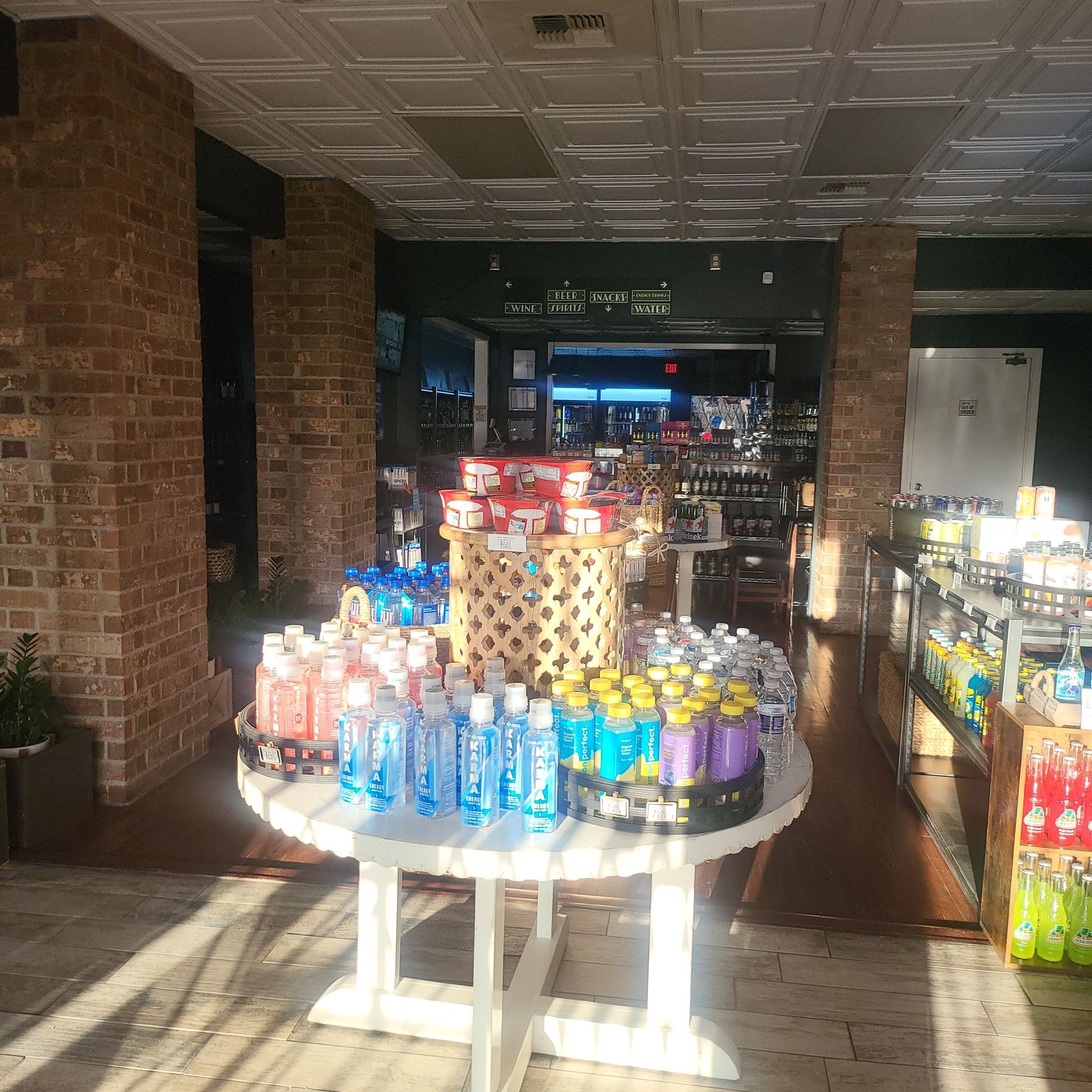 Convenience store aisle with a round display table of colorful bottled drinks in bright sunlight