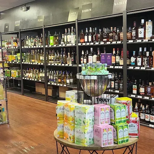 Liquor store aisle with shelves of bottles and a display table of colorful packaged goods