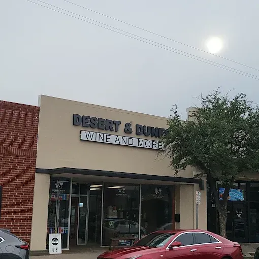 Storefront of Desert & Dune Wine and More with red brick facade and parked cars outside