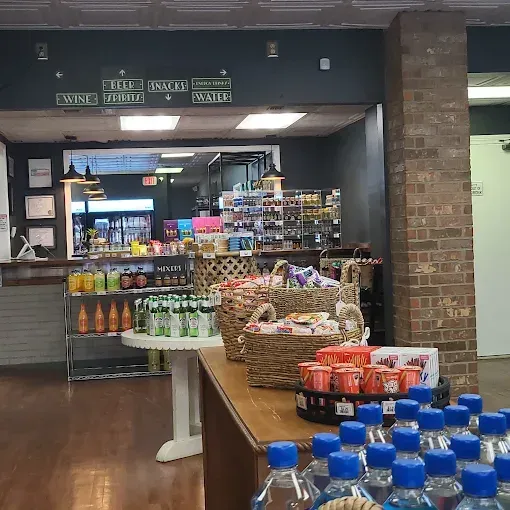 Grocery store display with bottled water, snacks, and produce near a market counter