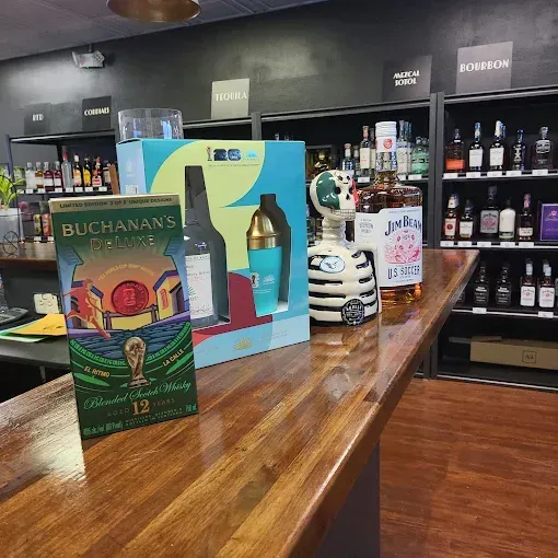 Liquor store display with Buchanan’s whiskey box, bottle, and other spirits on wooden shelves