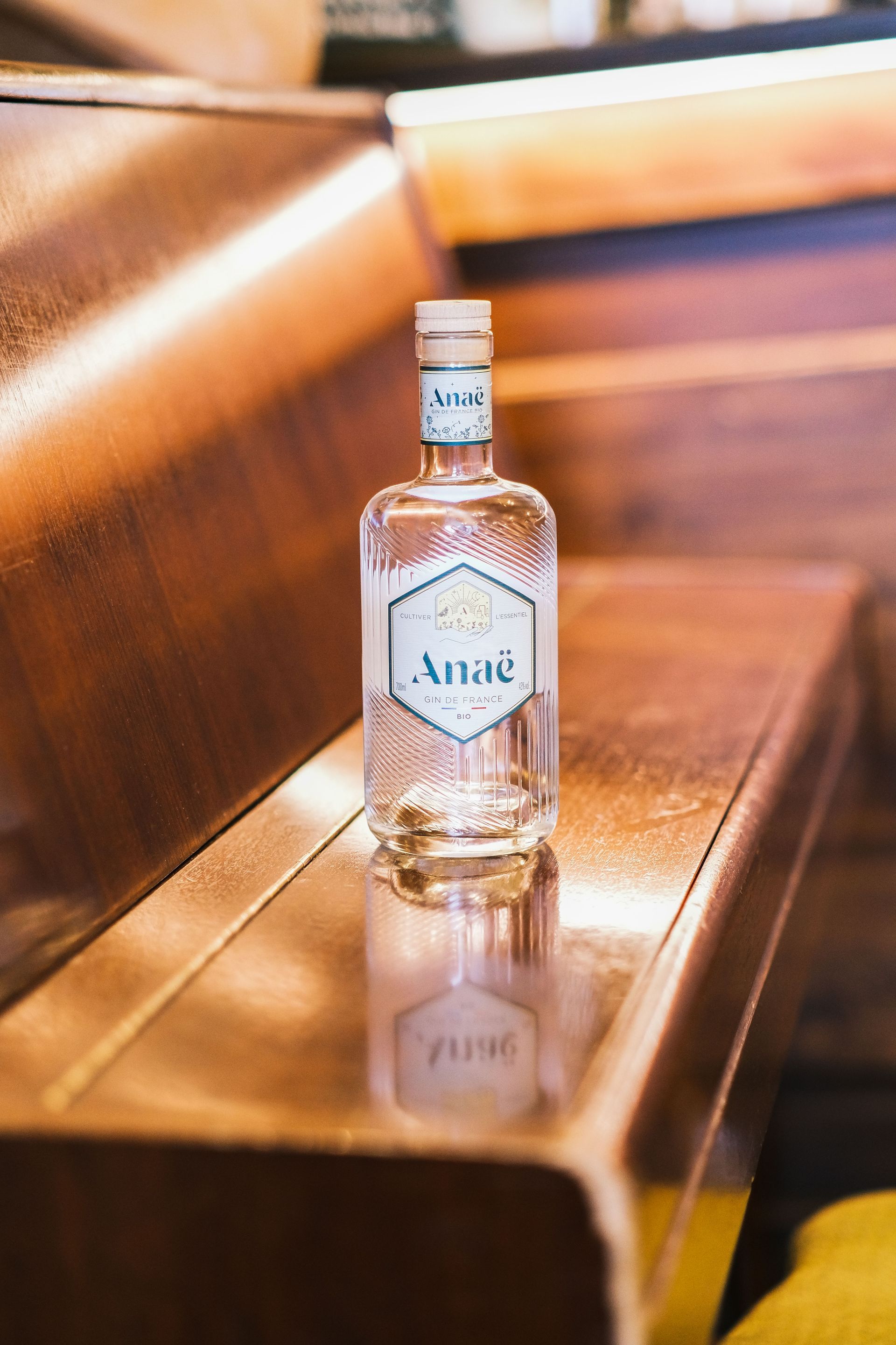 Bottle of Absolut vodka on a wooden bench in warm indoor lighting