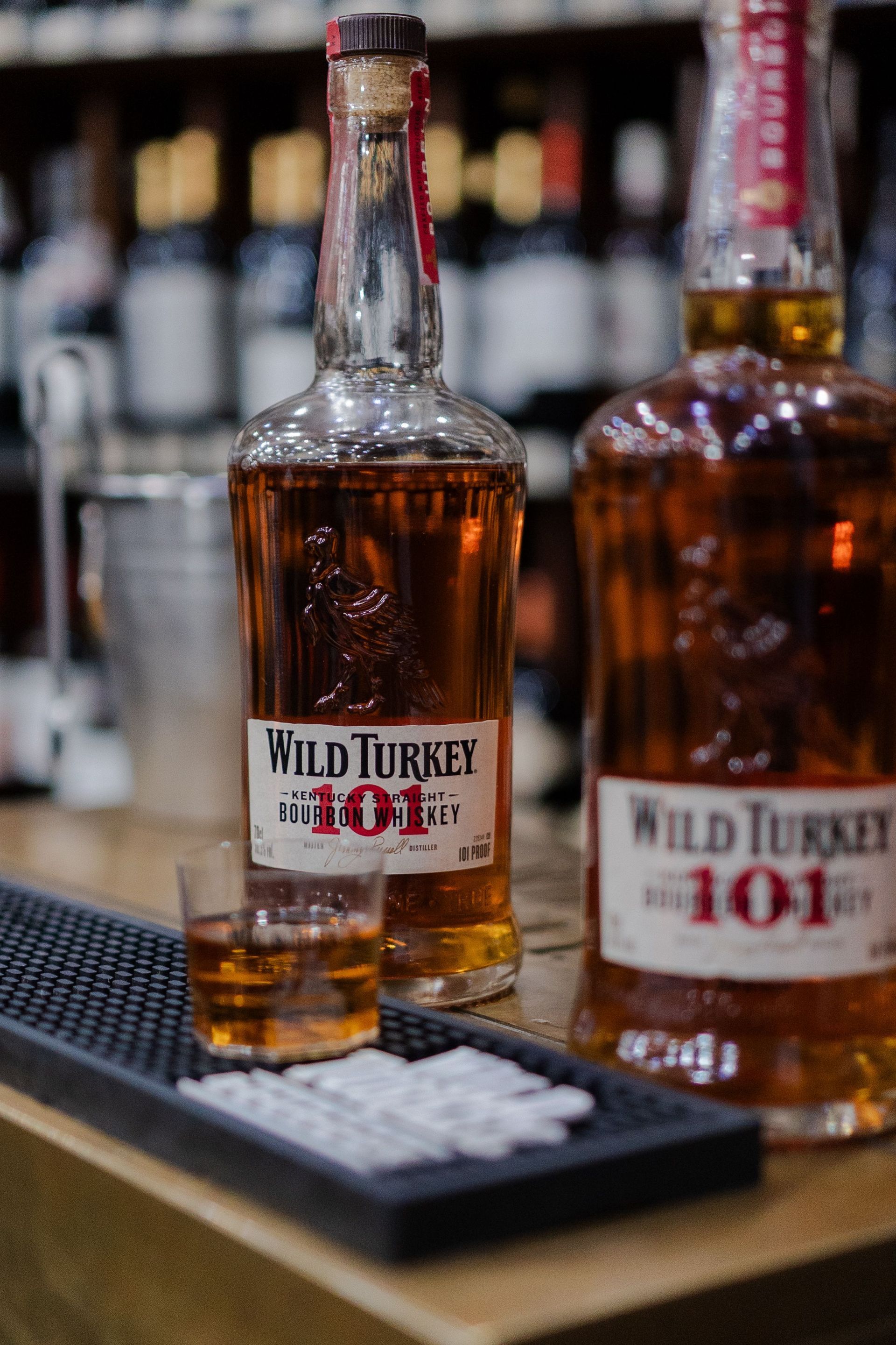 Wild Turkey 101 whiskey bottles on a bar counter with a shot glass tray