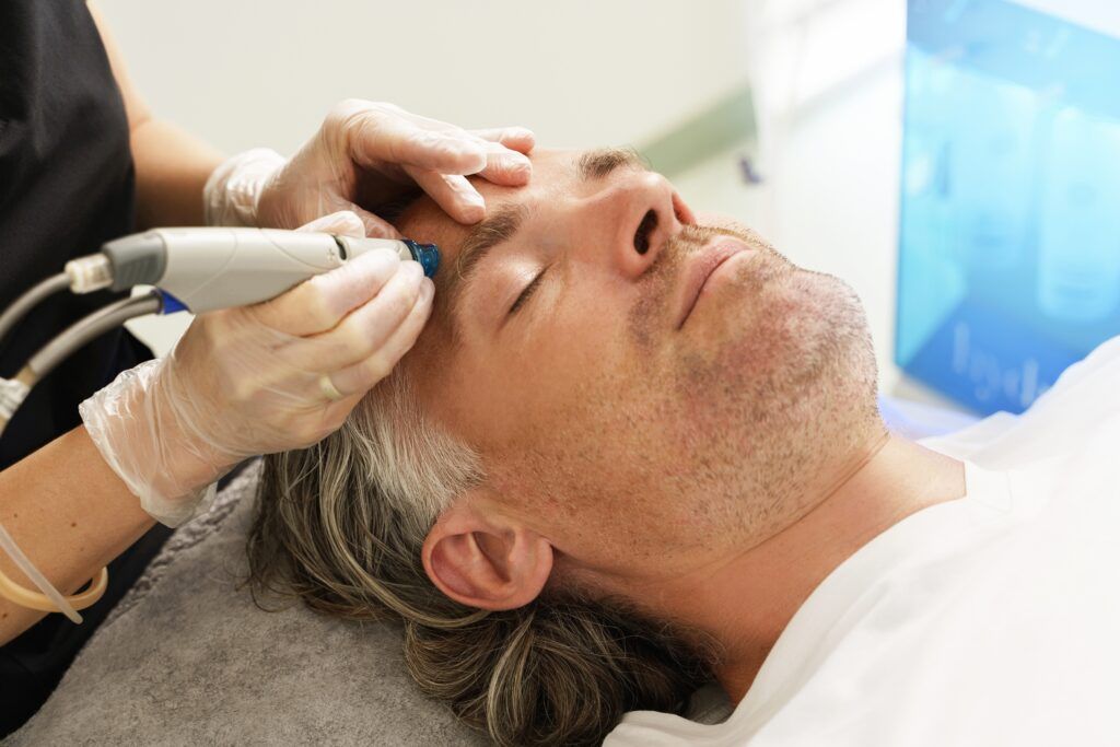 Person receiving a facial treatment; operator using a handheld device on forehead.