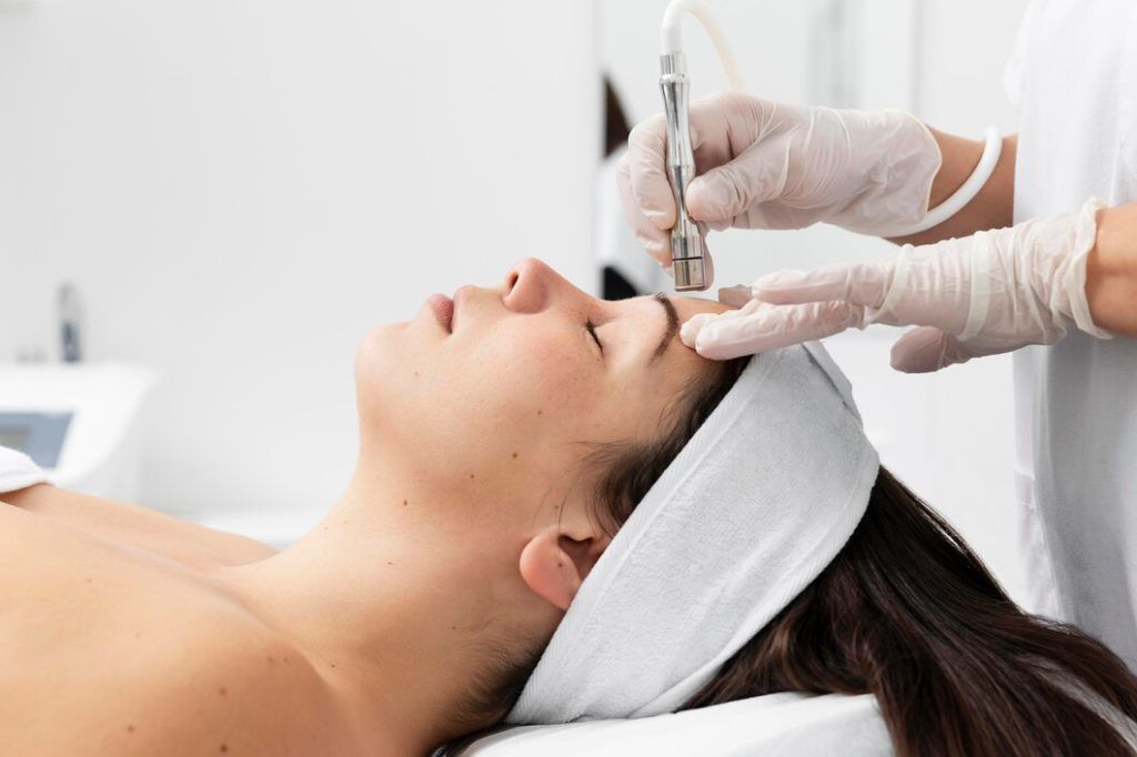 Person receiving a facial treatment with a handheld device, in a clinic setting.
