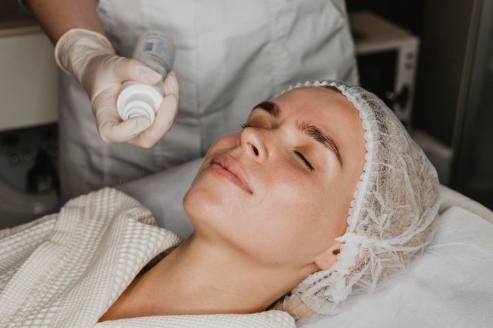 Person receiving facial treatment, being sprayed with product. Inside spa.