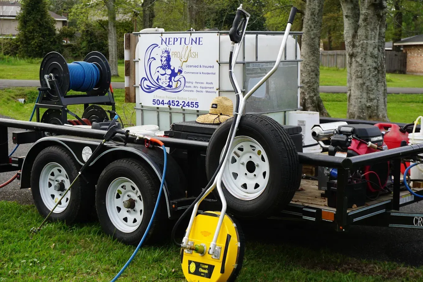 Trailer-mounted water tank and pump equipment on grass, with hoses and a yellow pressure washer.