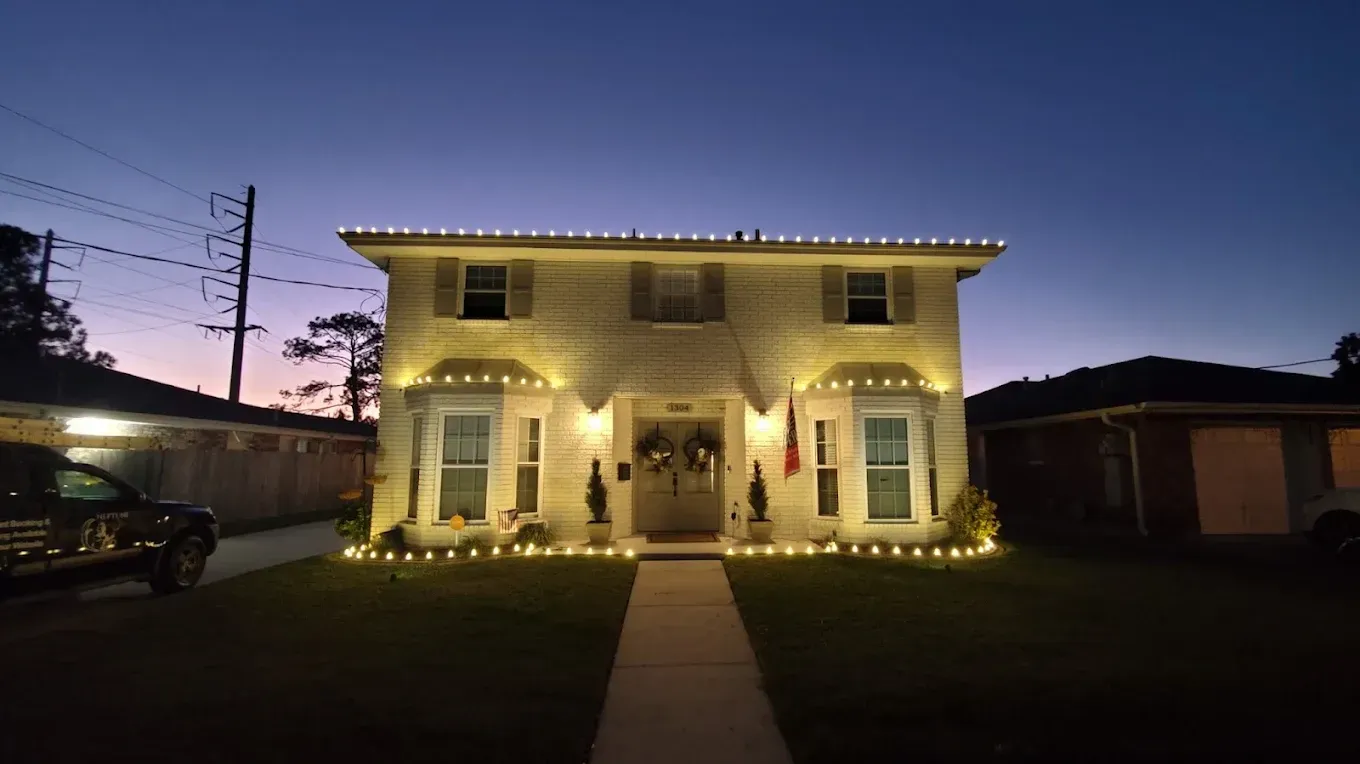 Lit two-story house at dusk with a front walkway and illuminated windows and porch lights