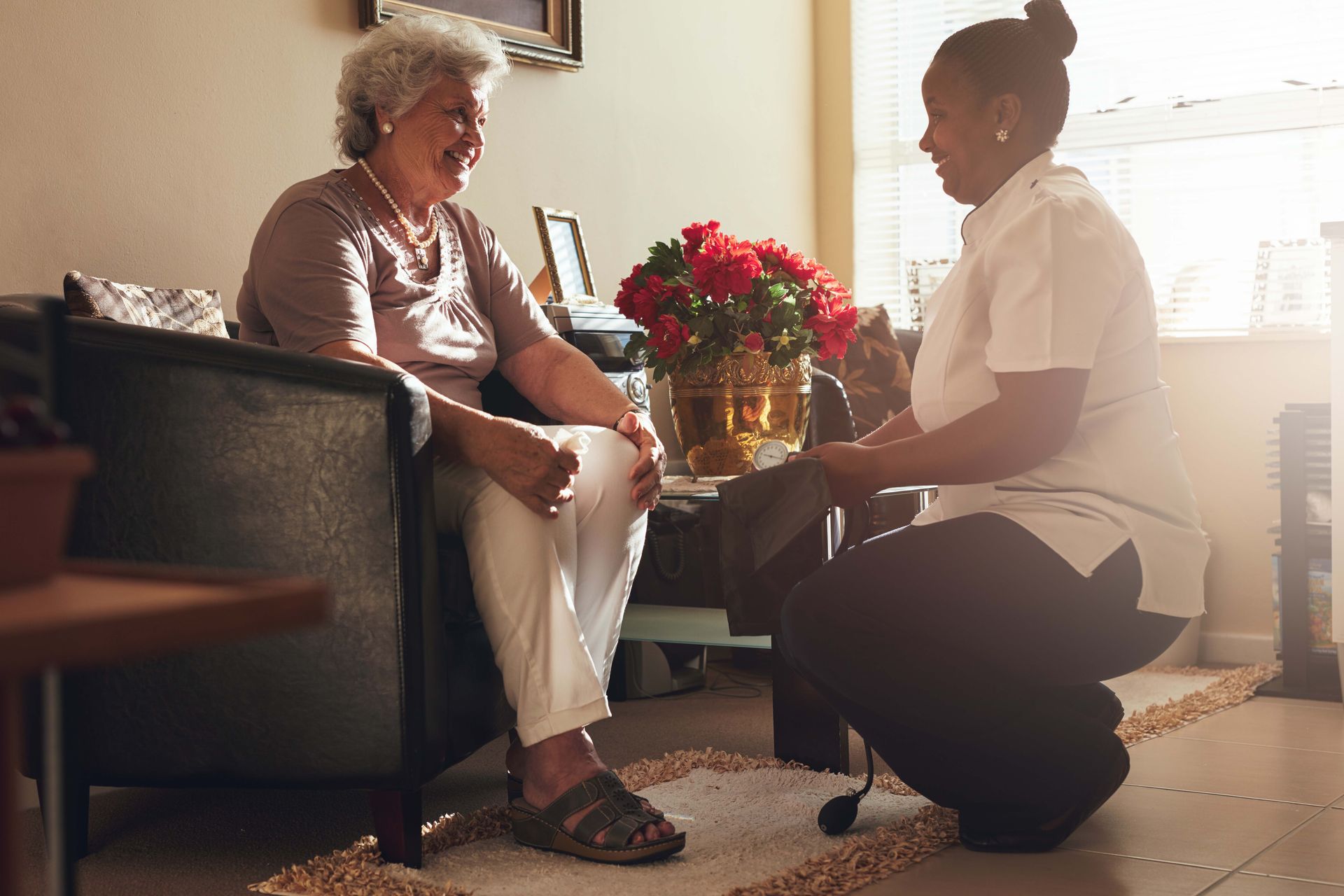Elderly person smiles as caregiver assists, indoors.