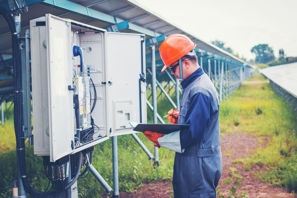 A Man in a Hard Hat is Standing in Front of a Solar Panel — Spot On Solar International in Newcastle, NSW
