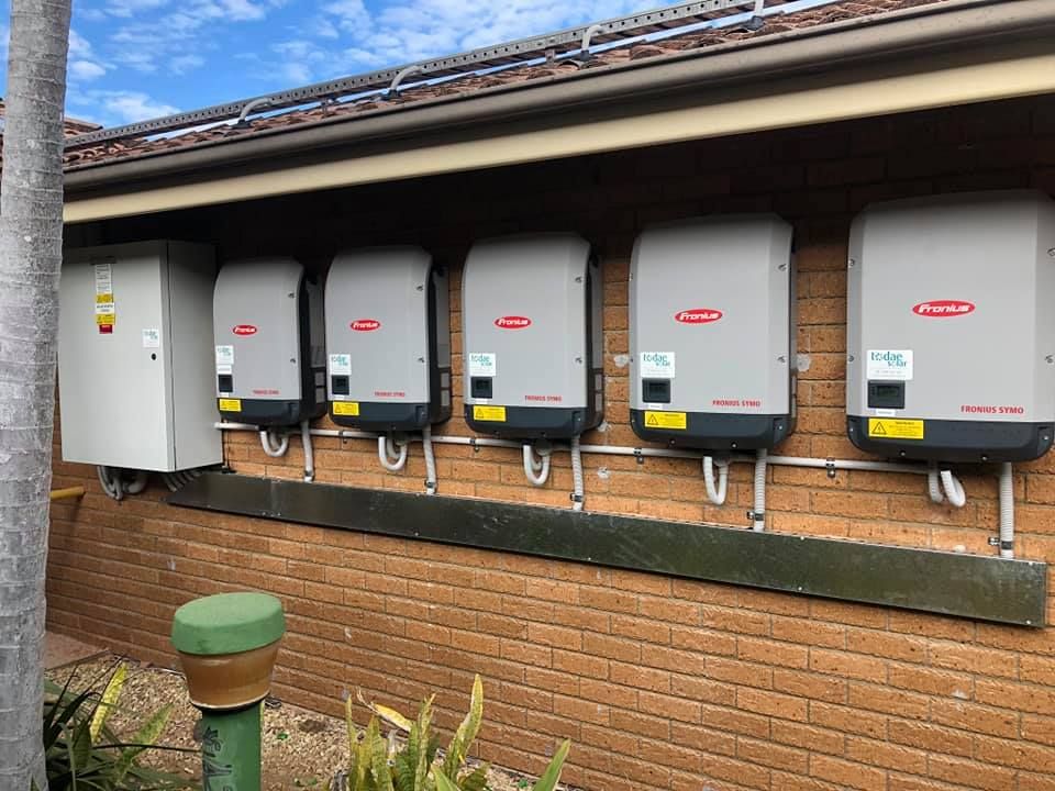 A Row of Solar Panels Are Mounted on the Side of a Brick Building — Spot On Solar International in Beresfield, NSW
