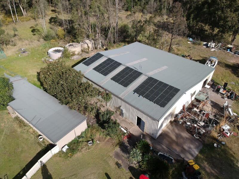 An Aerial View of a Warehouse With Solar Panels on the Roof — Spot On Solar International in Port Stephens, NSW