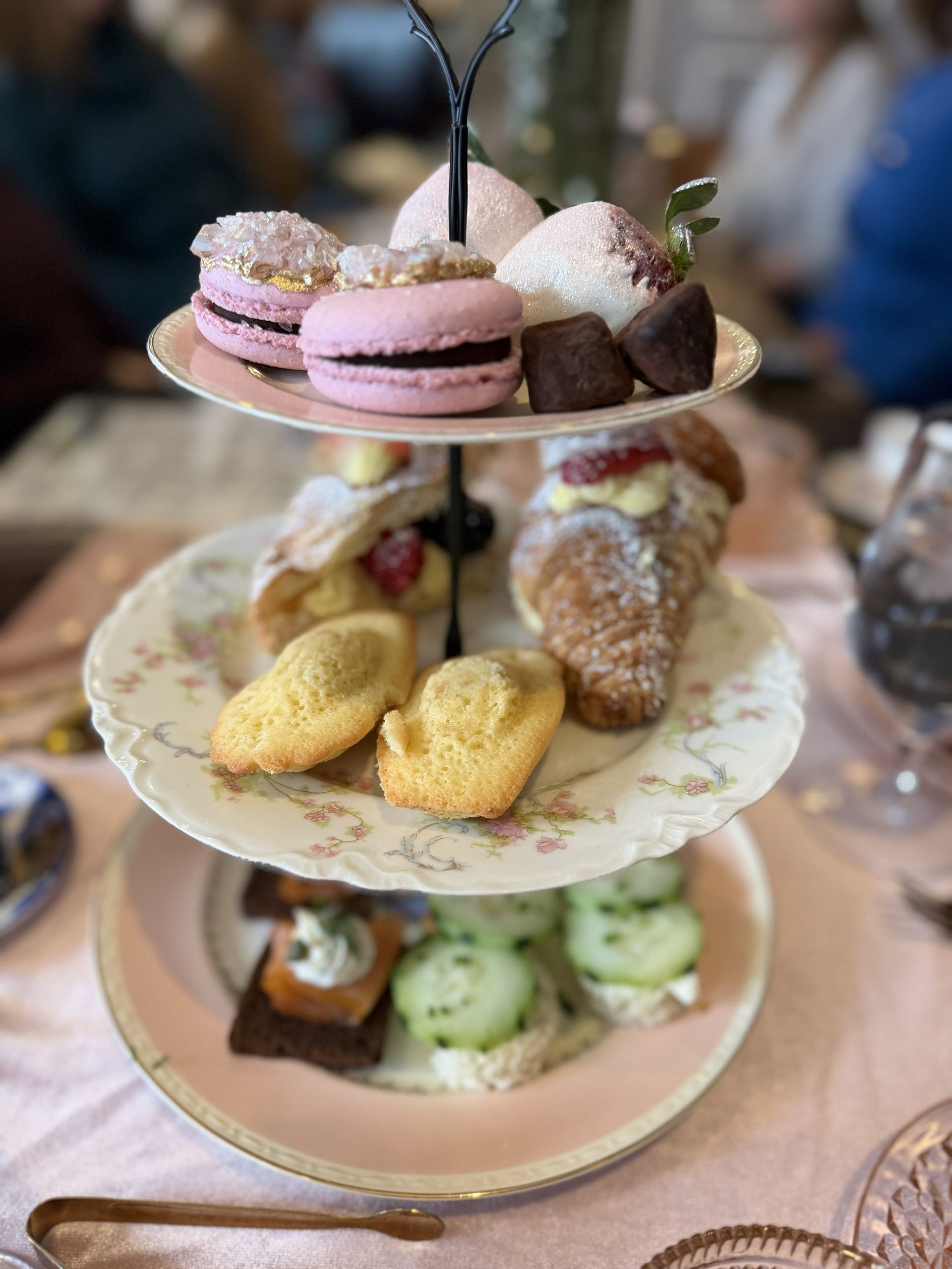 Three-tier dessert stand with assorted pastel pastries and macarons on a table