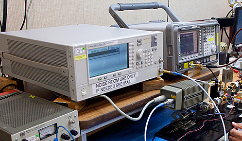 Automated lab machine inspecting a circuit board on a white workbench