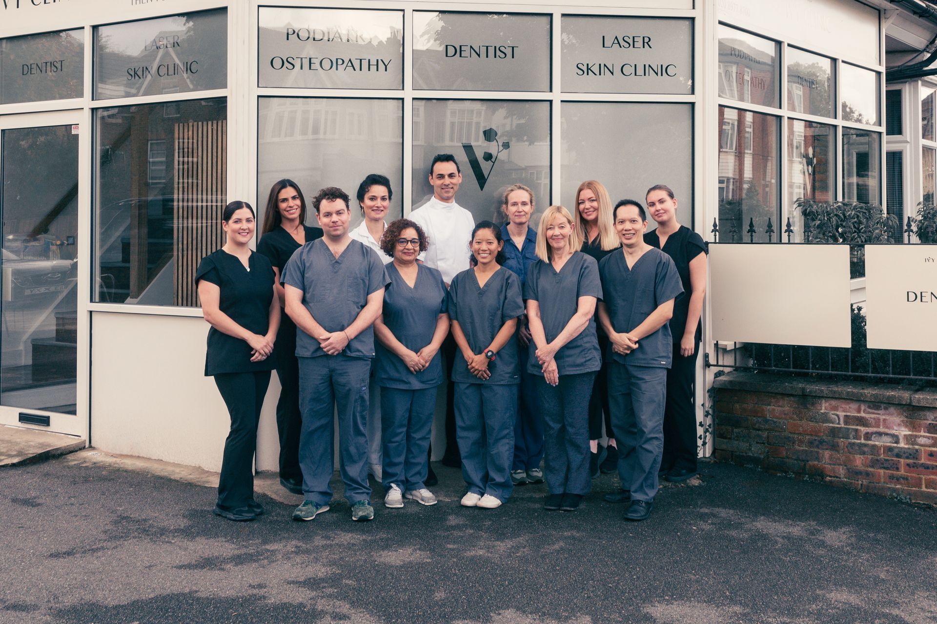 Staff of a medical clinic posing outside the building with glass windows.