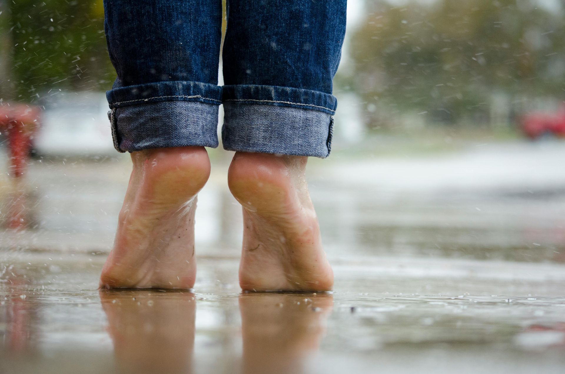 Bare feet, blue jeans, jumping in puddles on a wet sidewalk.